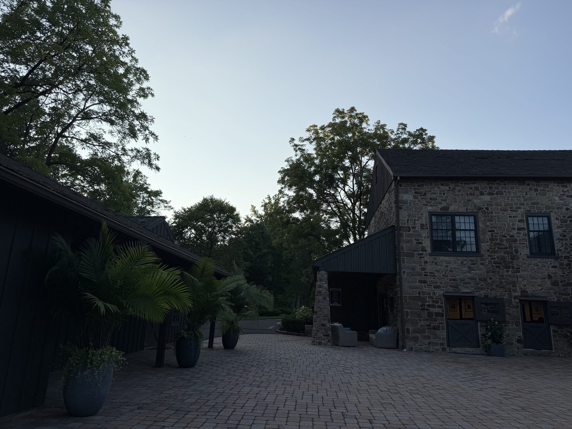 The brick courtyard between the stone barns at dusk