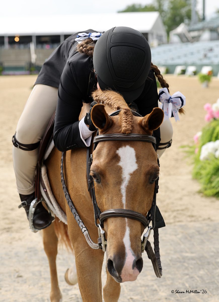 A rider hugging their pony after a round
